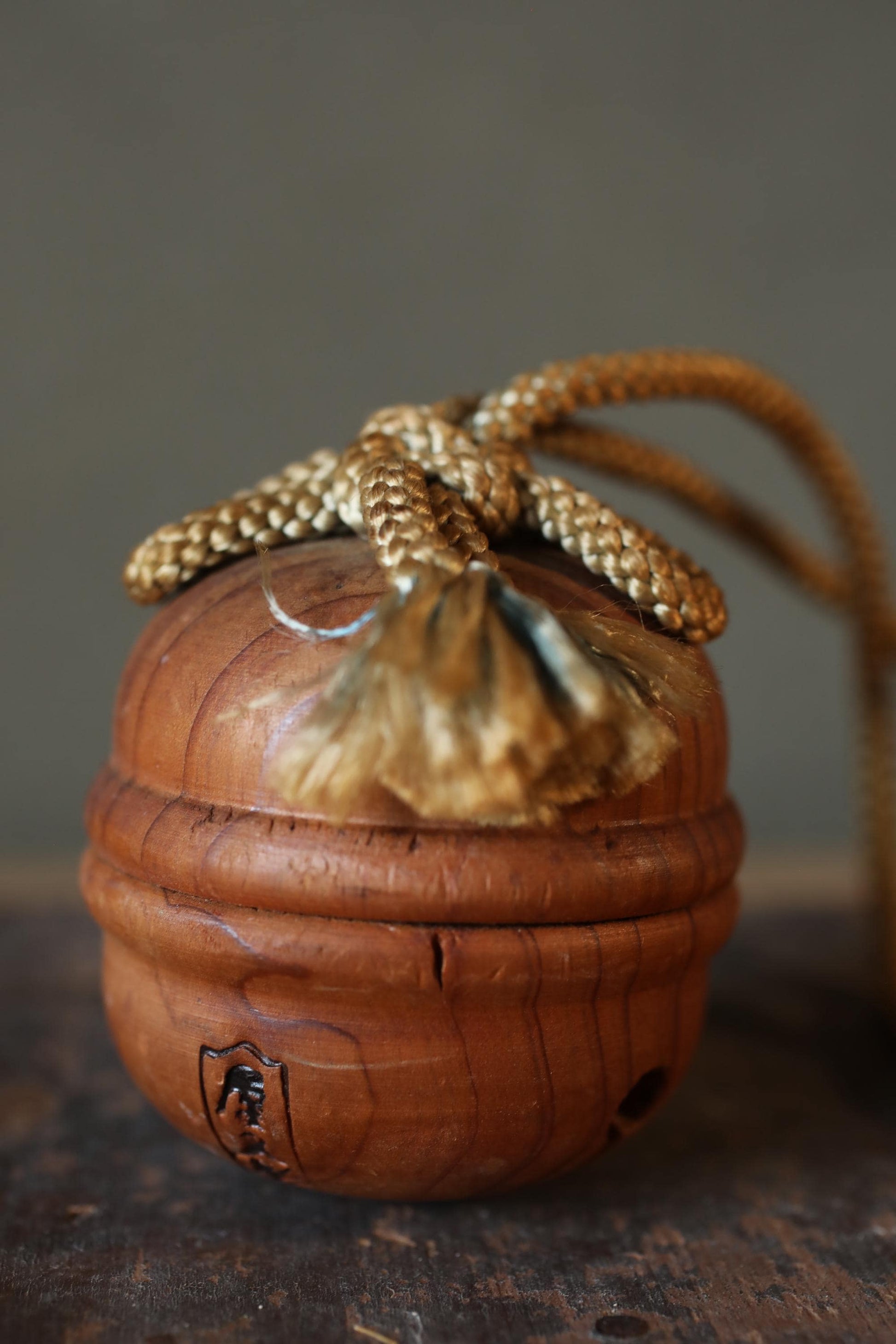 A wooden object with a curved shape and a small hole on the side, resting on a wooden surface.