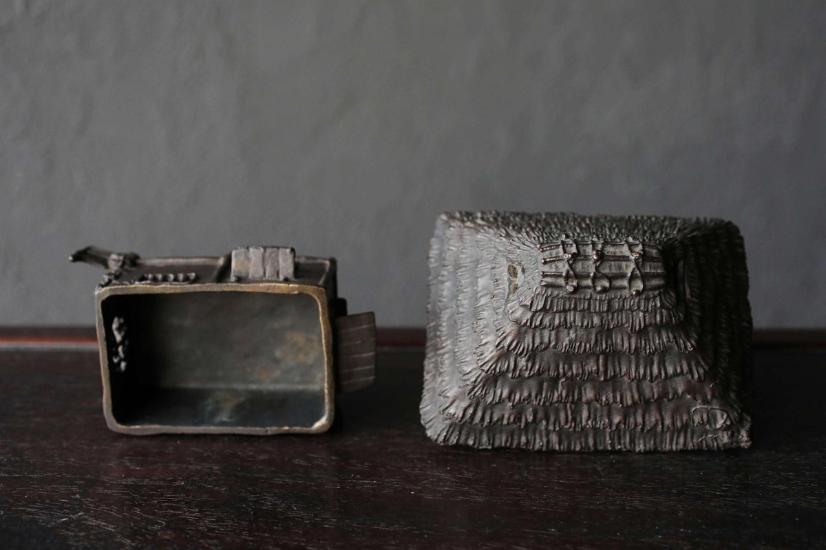 a small, square-shaped object with a textured surface, placed next to an open, rectangular object with a similar textured surface.