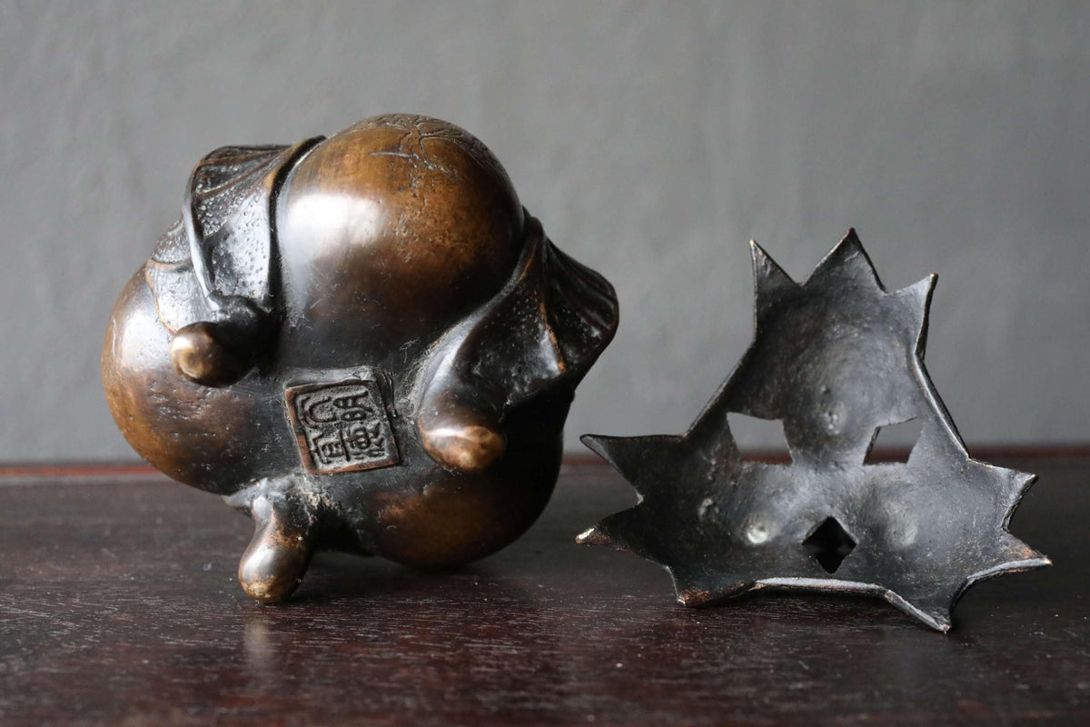 a pair of bronze figurines, one standing upright and the other lying on its side, both placed on a dark surface.
