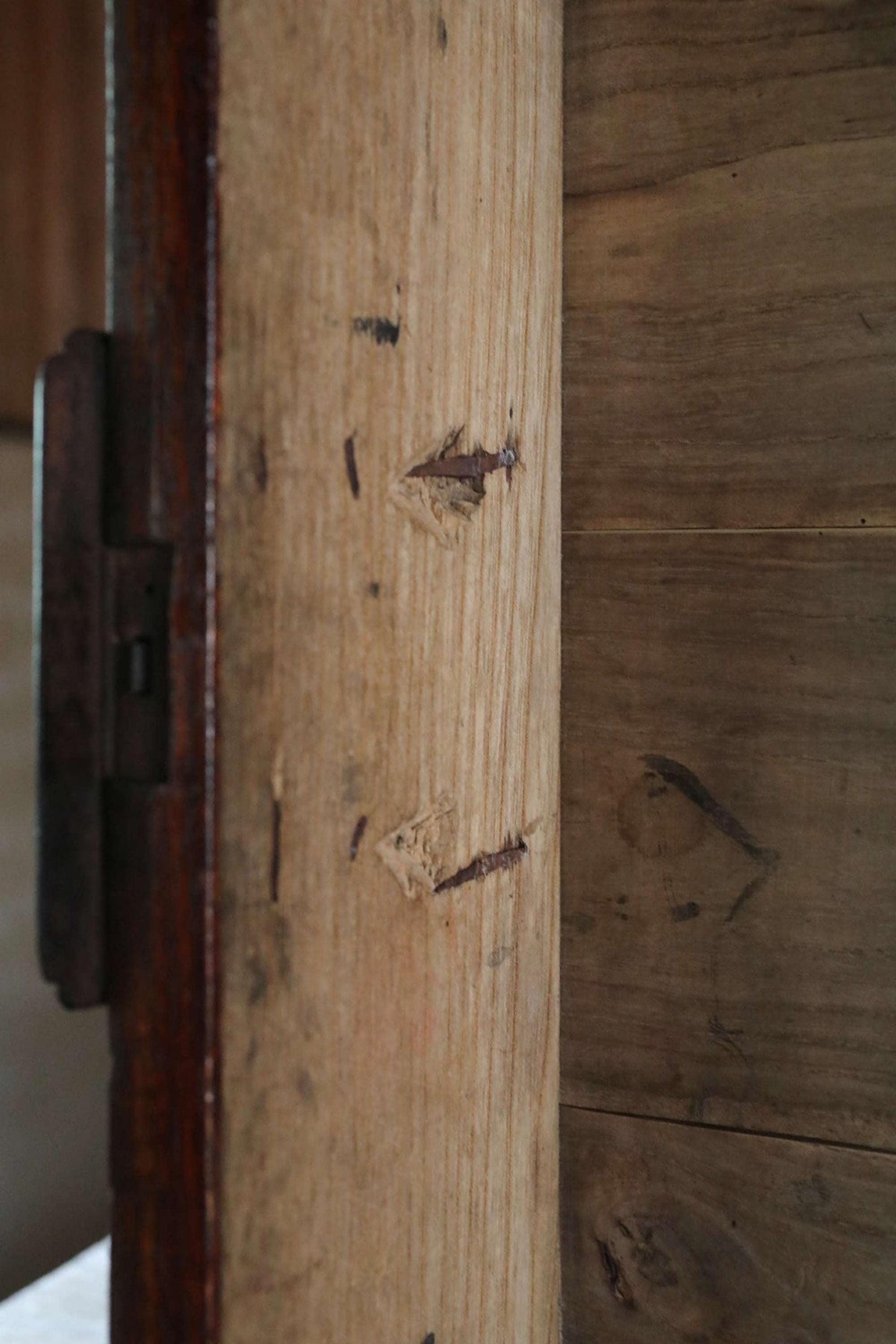 a close-up view of a wooden surface with visible signs of wear and tear, including a few nails and a small hole.