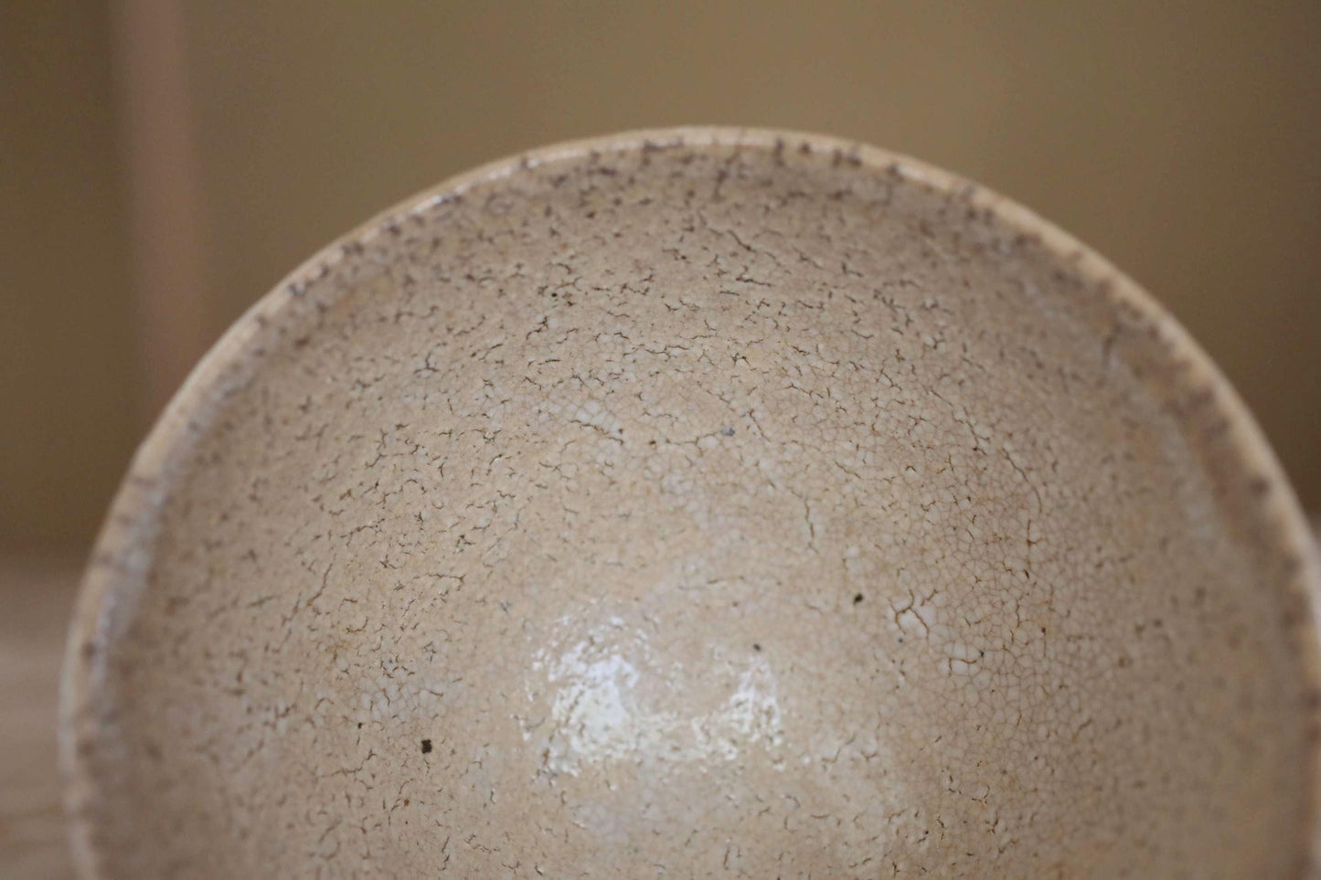 A close-up view of a textured, speckled ceramic bowl or dish with a rough, uneven surface.