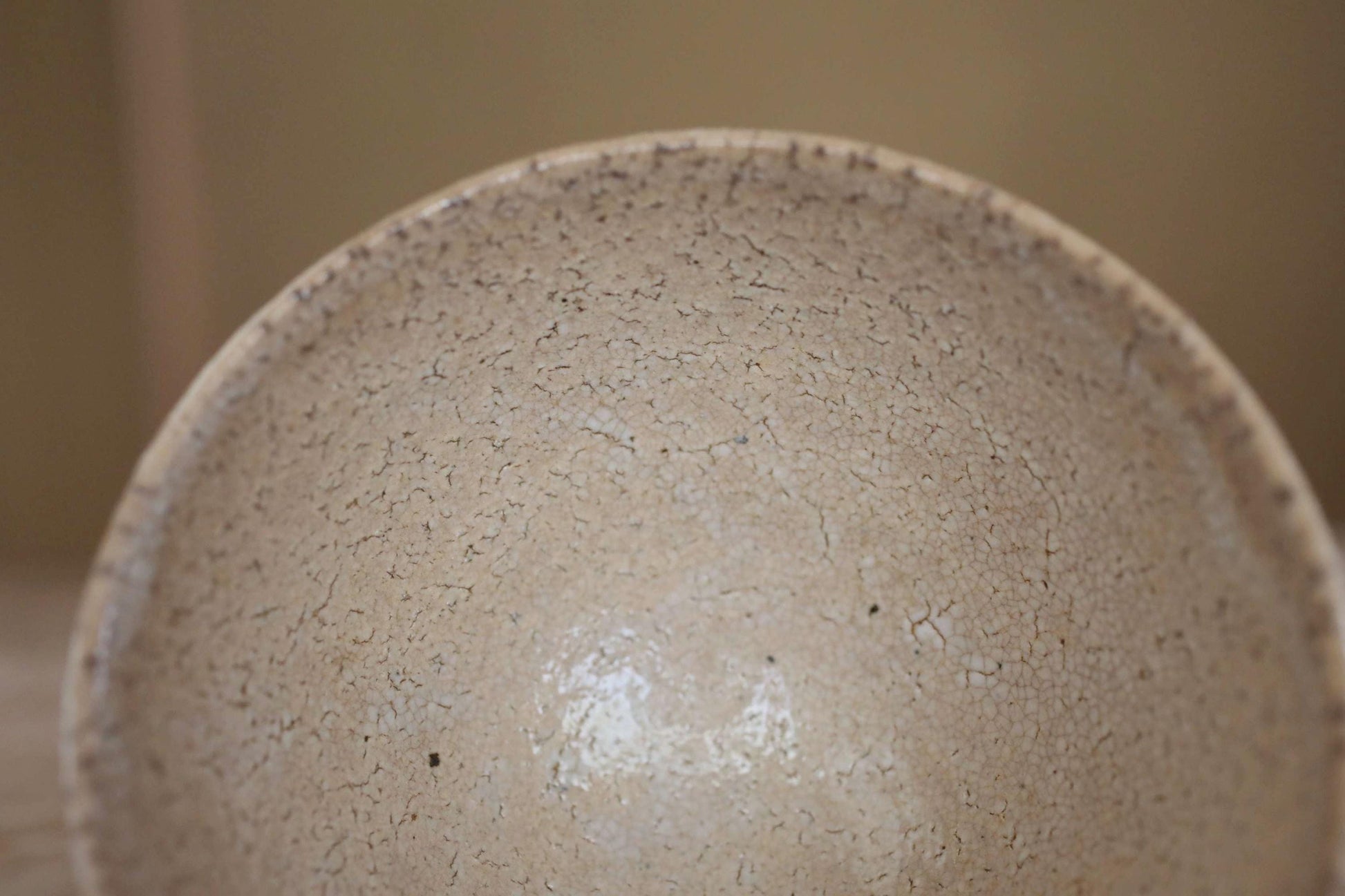 A close-up view of a textured, speckled ceramic bowl or dish with a rough, uneven surface.