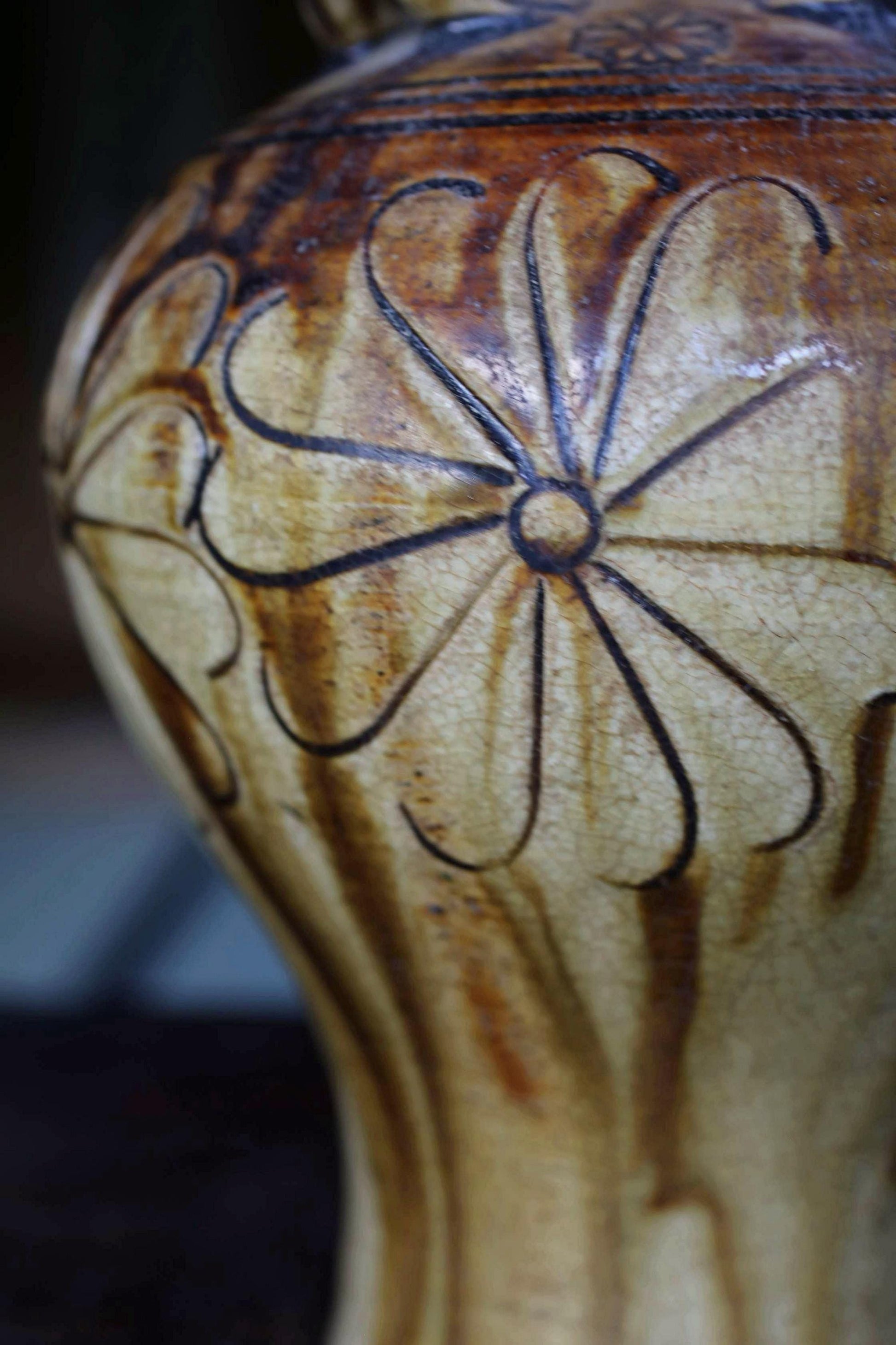A close-up view of a ceramic vase with a floral design on its surface.