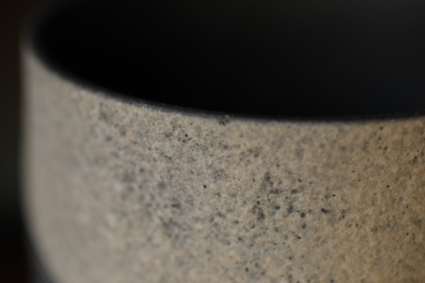 A close-up image of a textured ceramic or porcelain object, with a dark background.