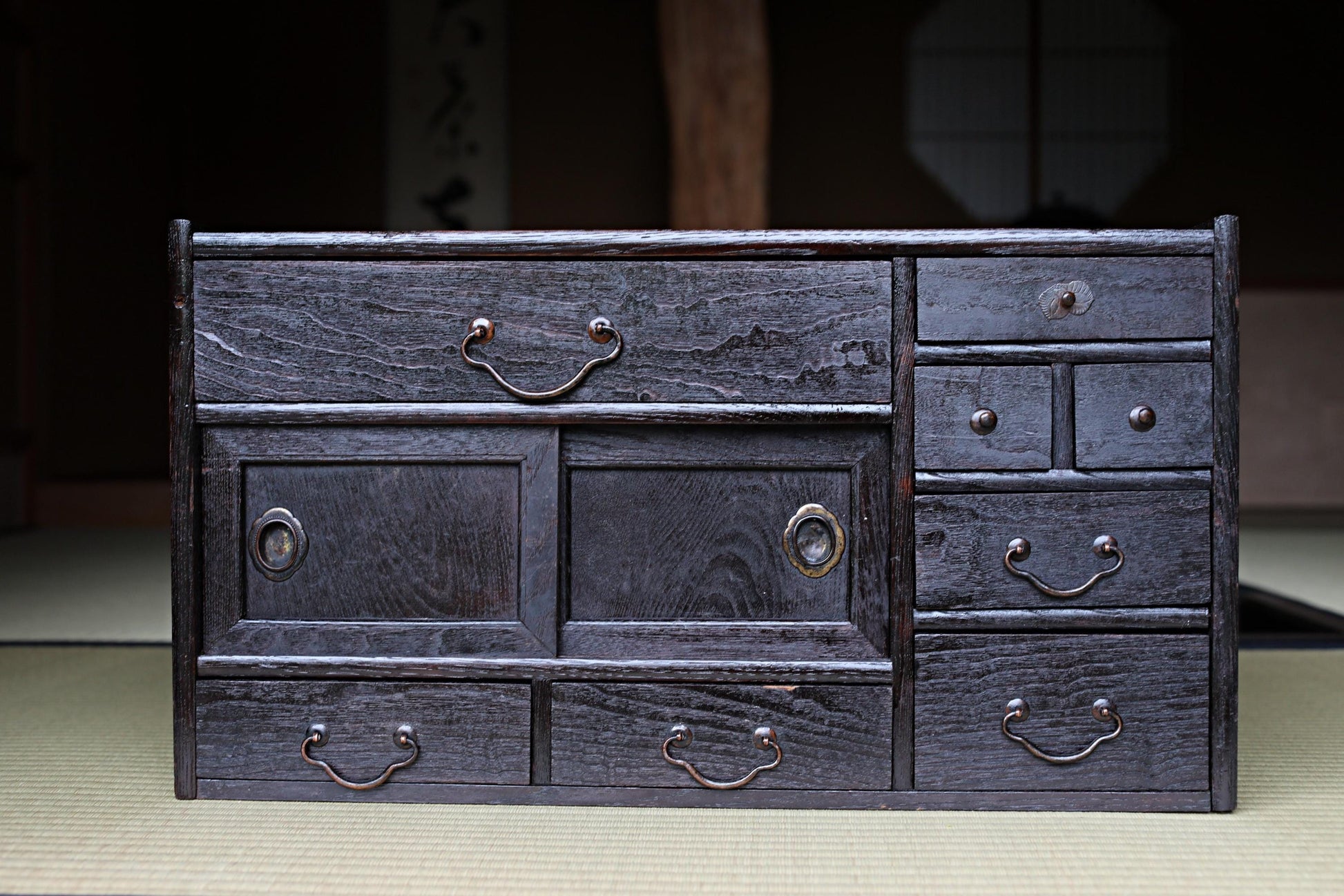 A dark wooden cabinet with multiple drawers and doors, featuring a traditional Japanese aesthetic.