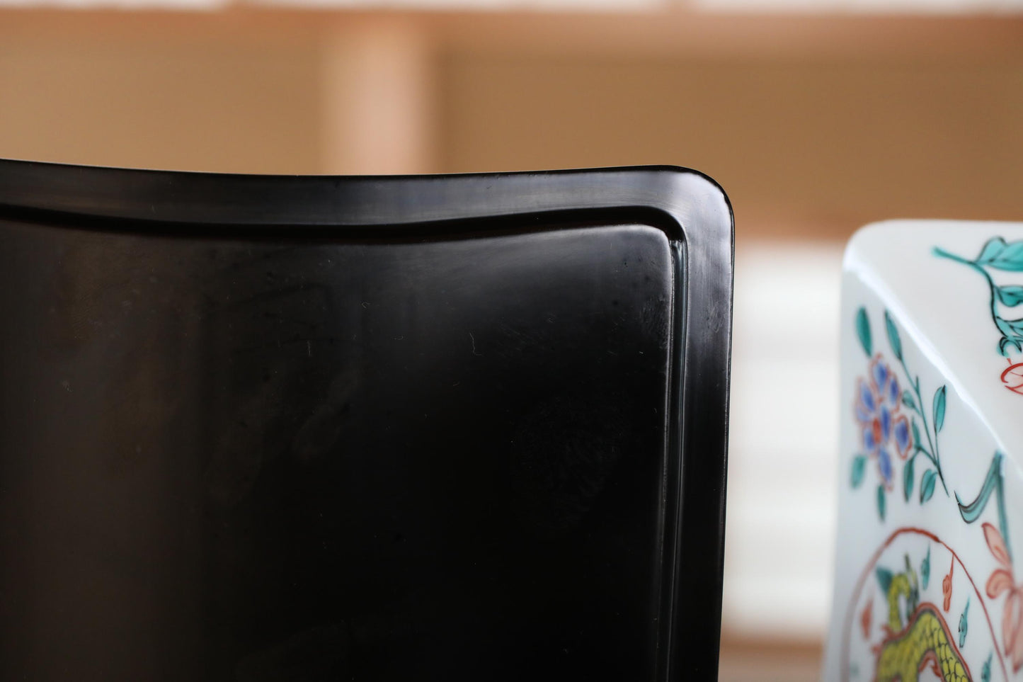 a close-up view of a black object, possibly a chair or a table, with a colorful, decorative object to the right.