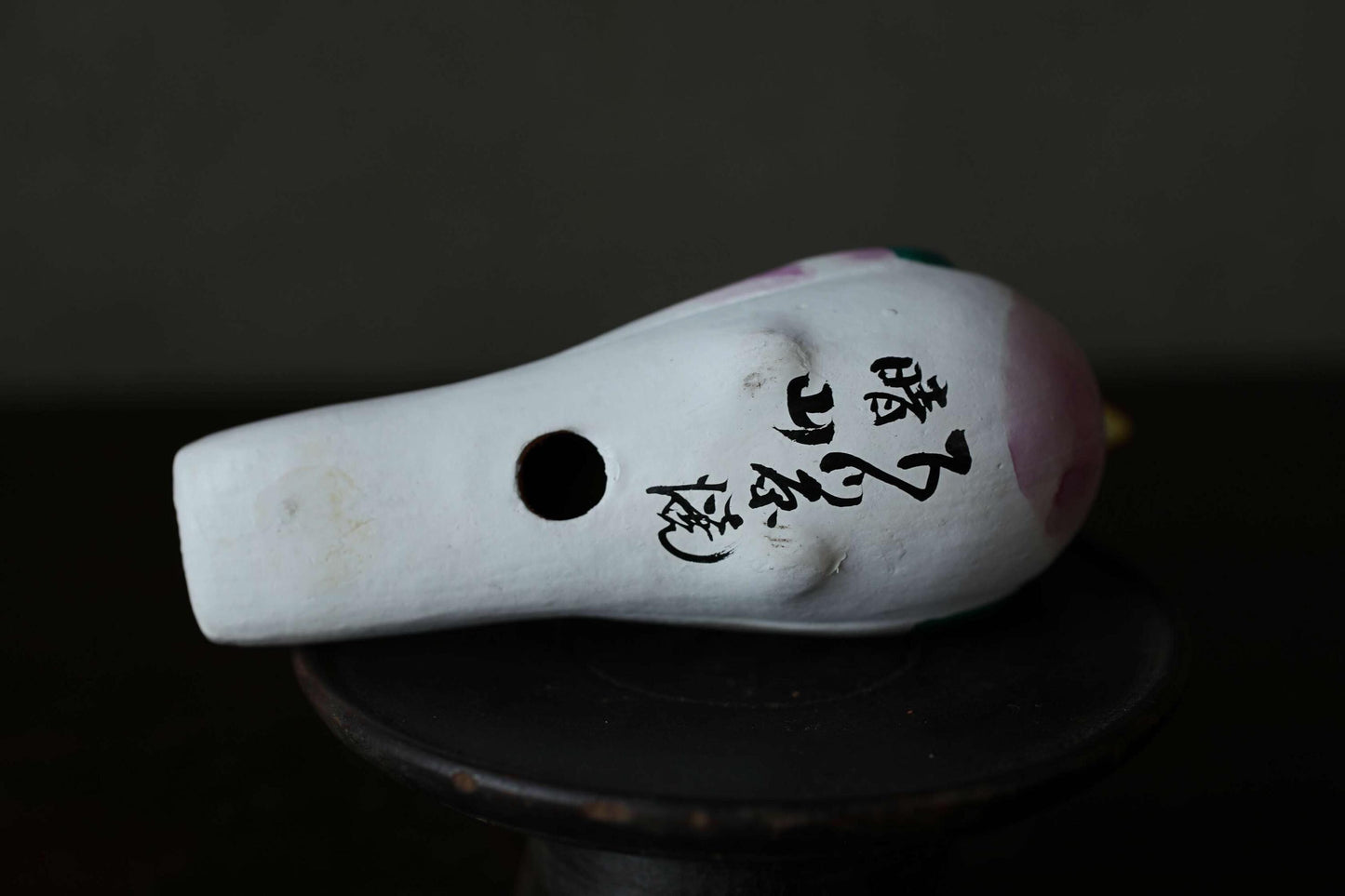 A white ceramic object with black text on it, sitting on a black surface.