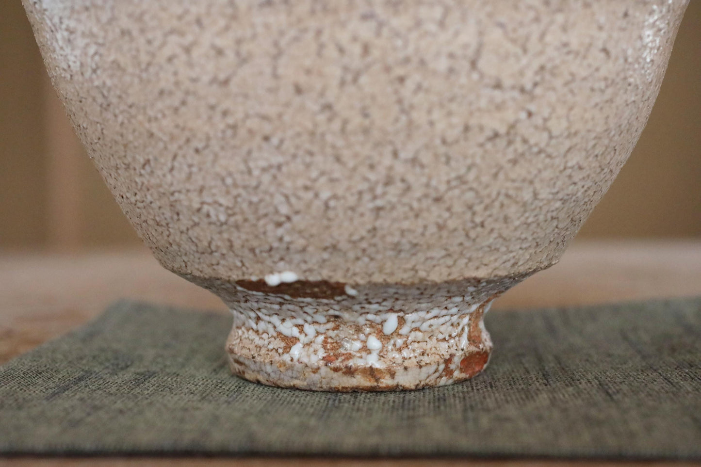 A close-up view of a ceramic bowl with a textured surface, resting on a textured surface.