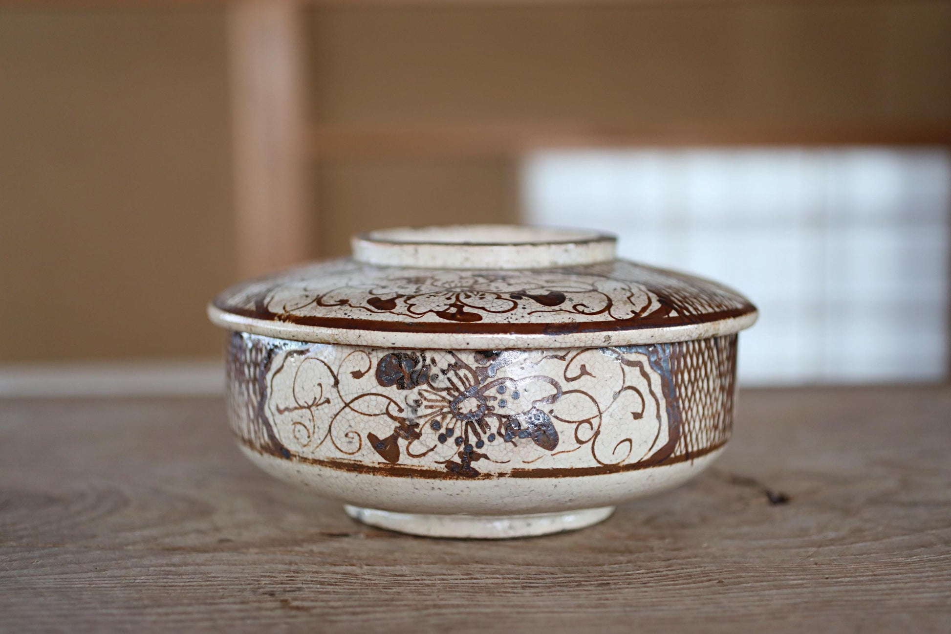 A decorative ceramic bowl with a floral pattern sits on a wooden surface.