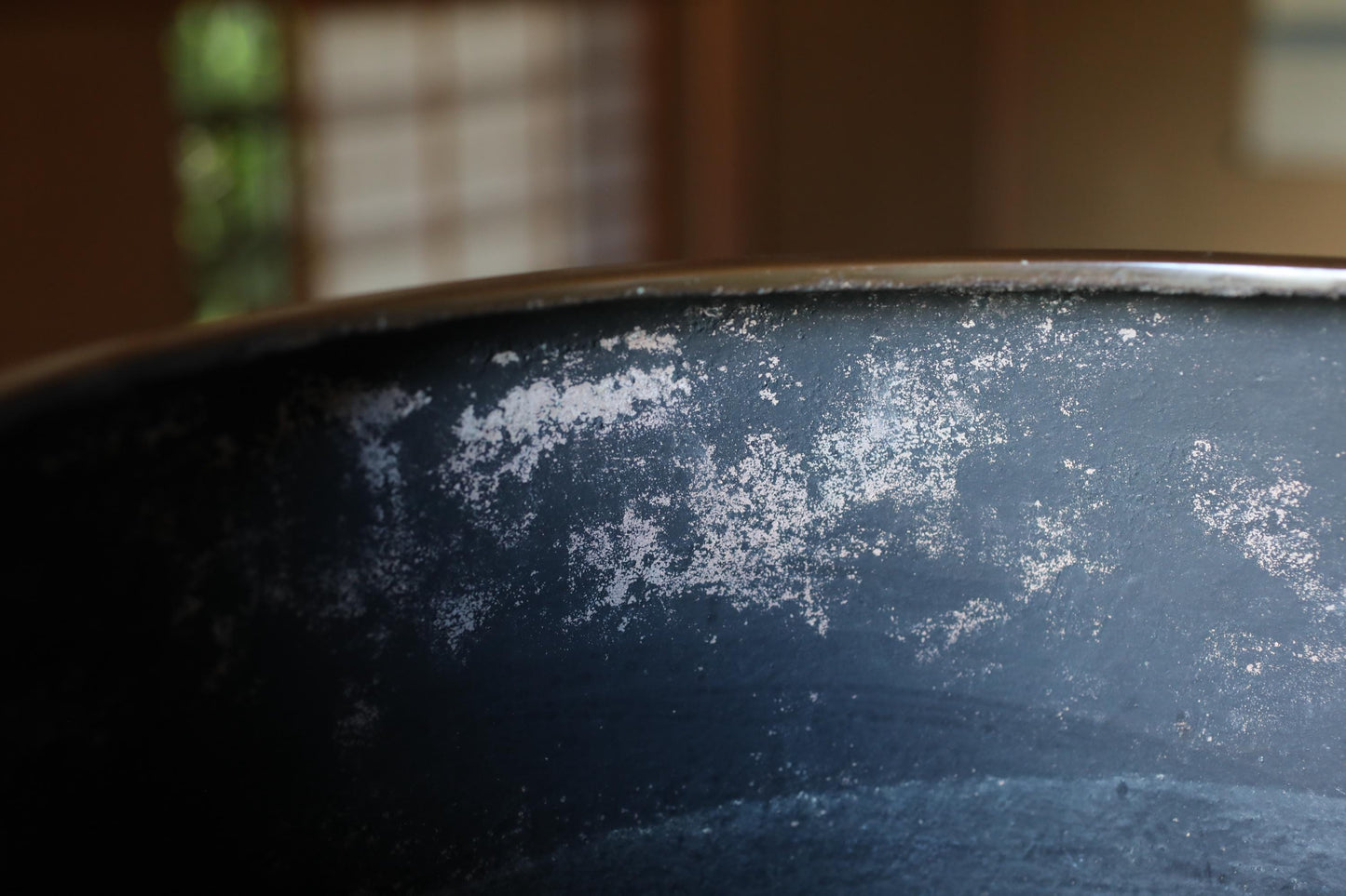 A close-up view of a black, dirty pot with white spots on its surface.