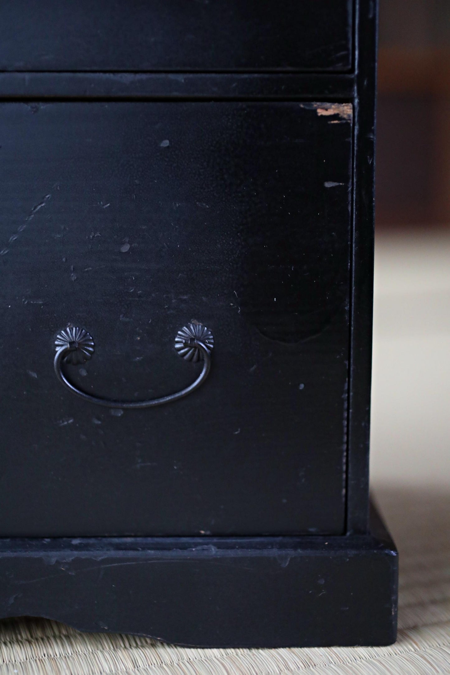 a close-up view of a black wooden drawer with a metal handle, sitting on a wooden surface.