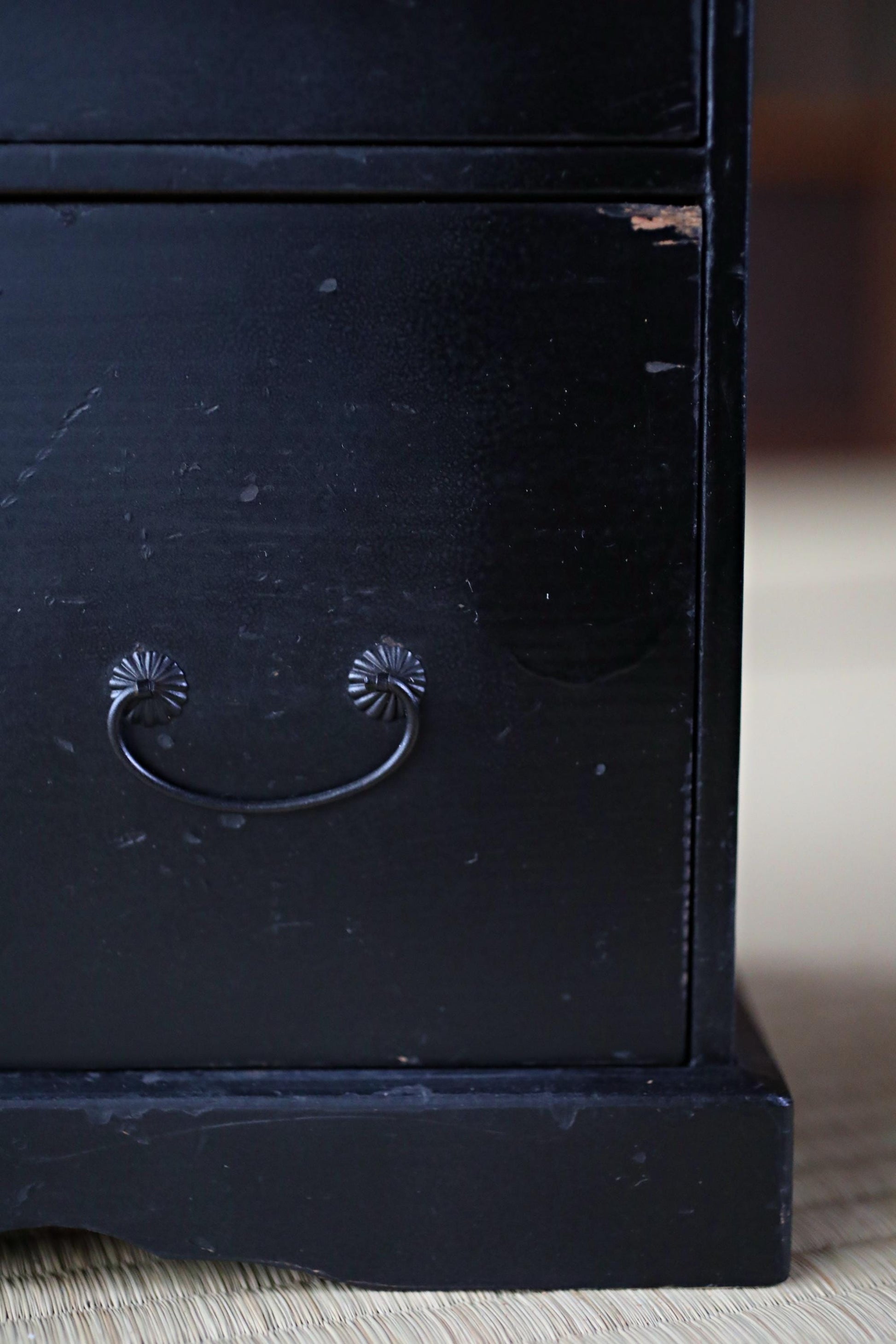 a close-up view of a black wooden drawer with a metal handle, sitting on a wooden surface.