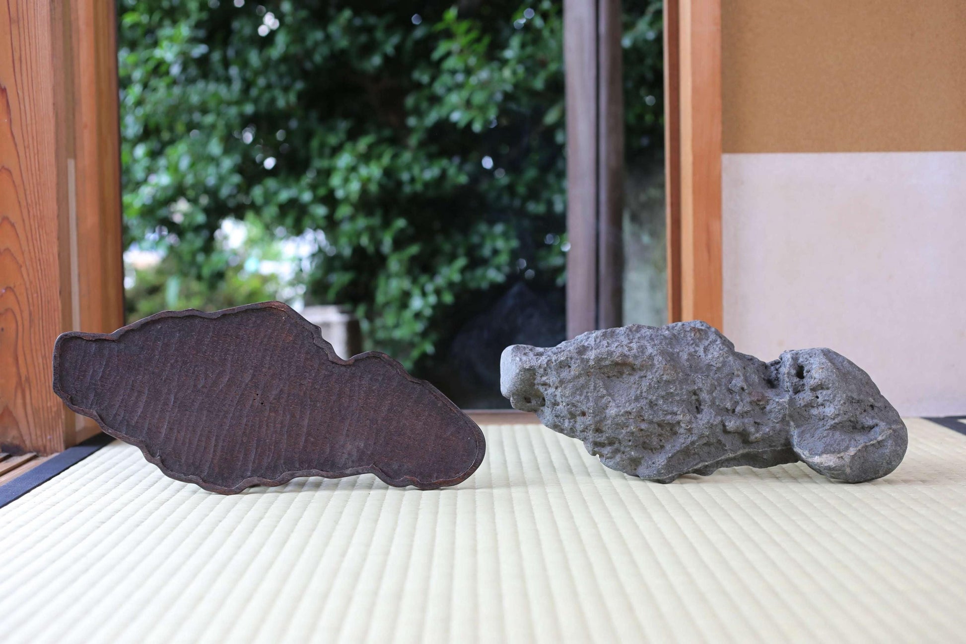 two large rocks, one dark and one gray, placed on a white surface.