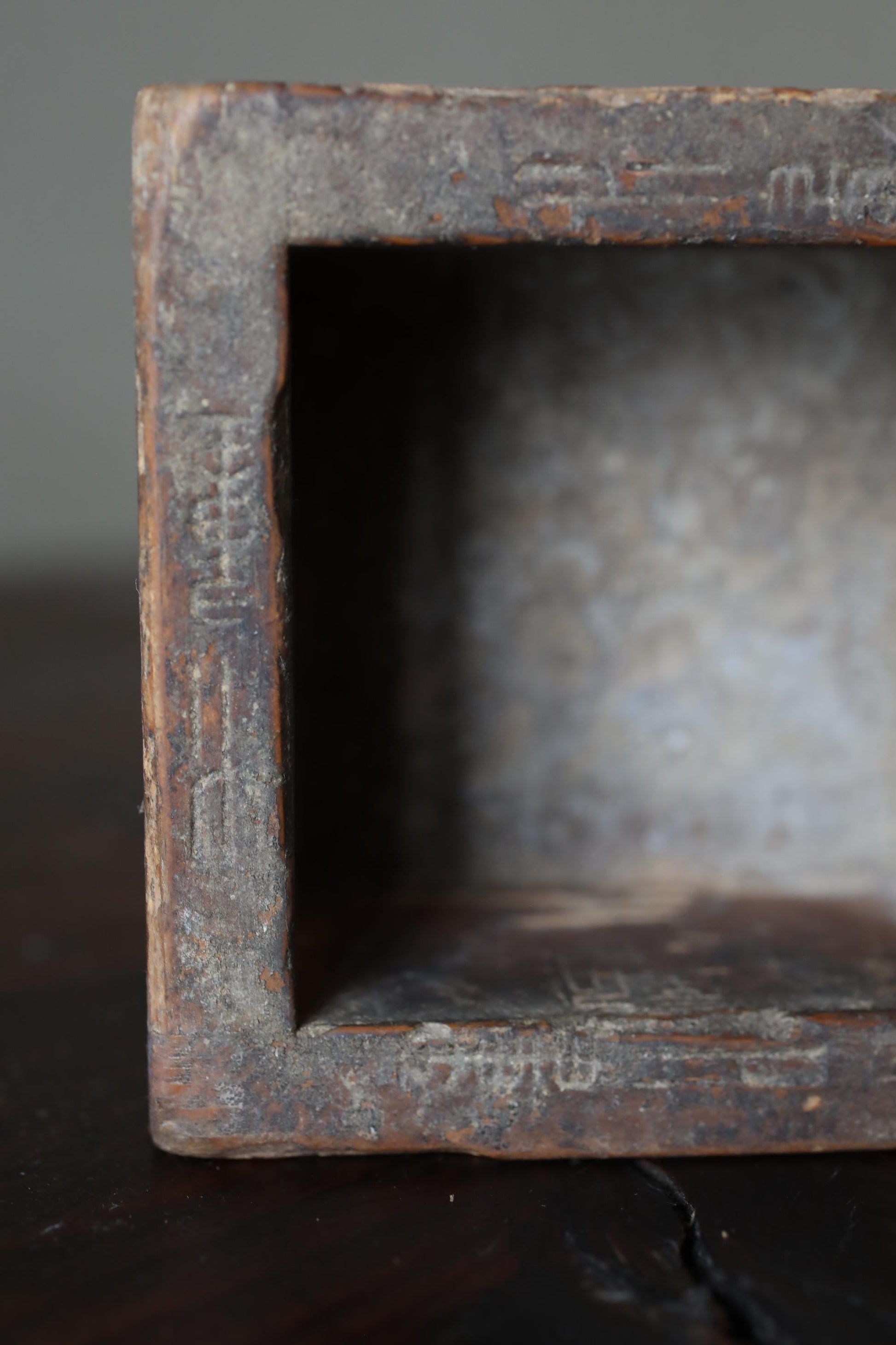 a close-up view of a weathered, rusted metal object with a carved design on its surface.