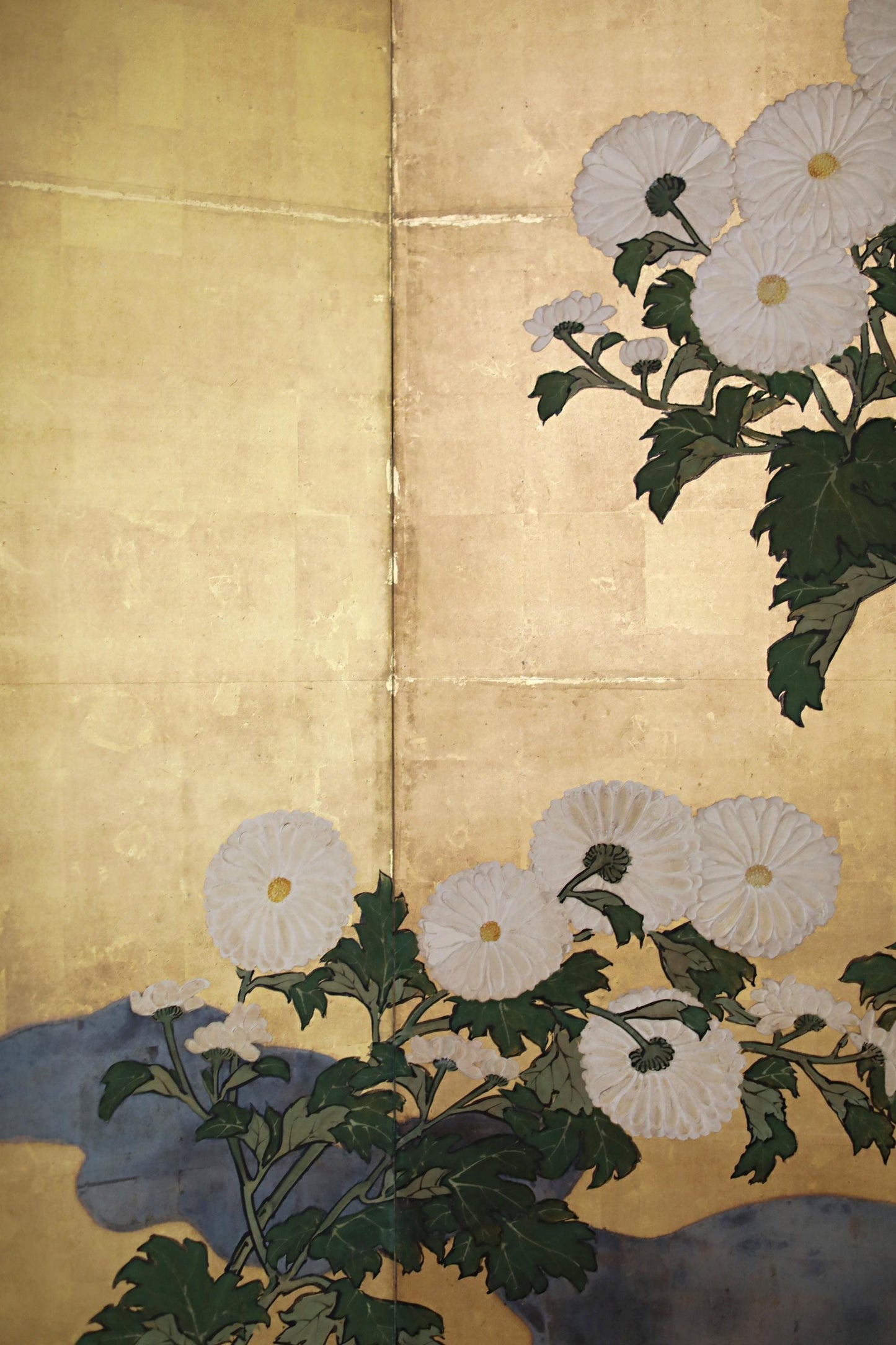 a close-up view of a white flower with green leaves, set against a golden background.