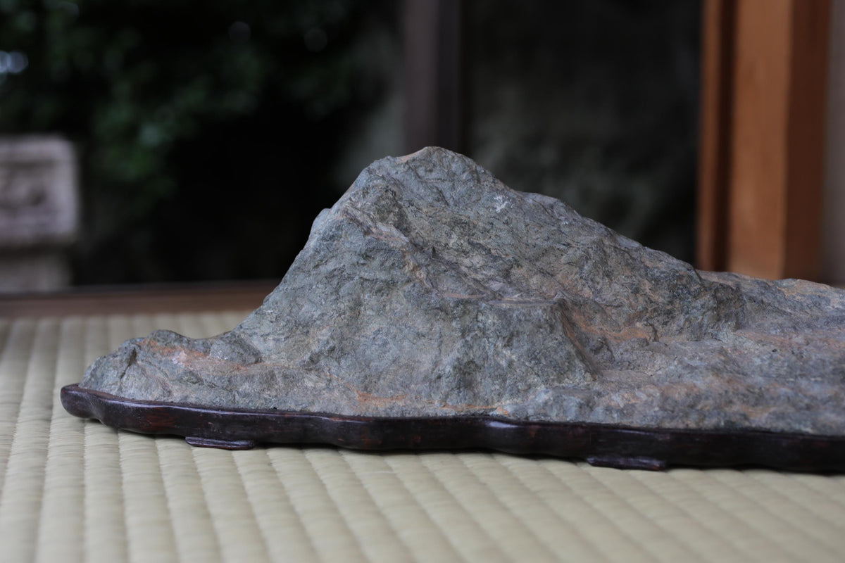 A close-up image of a rock formation, possibly a mountain or hill, placed on a wooden base or stand.