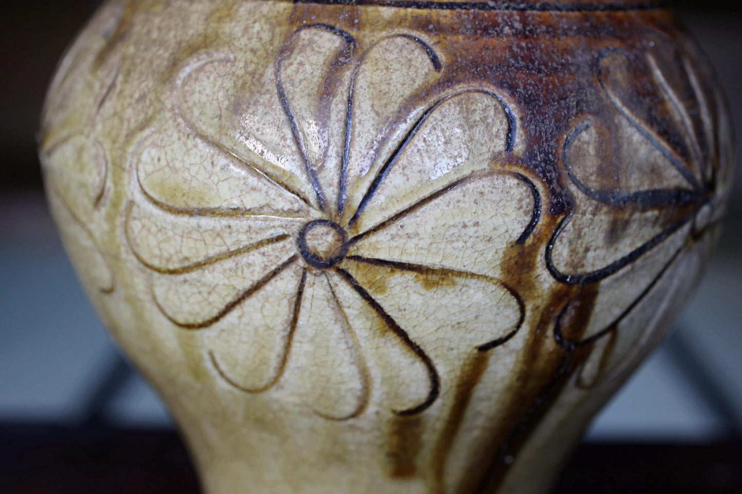A close-up view of a ceramic vase with a floral design on its surface.