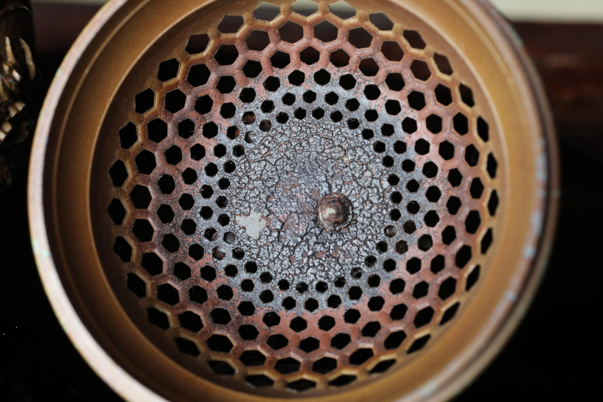 a close-up view of a metal object with a perforated design, possibly a piece of machinery or a container.