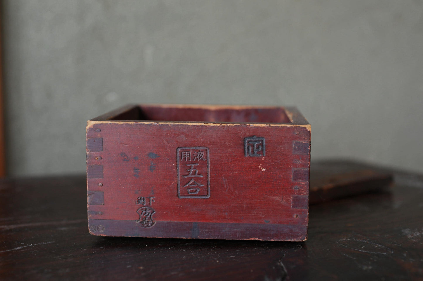 A red wooden box with Chinese characters on it, sitting on a dark surface.