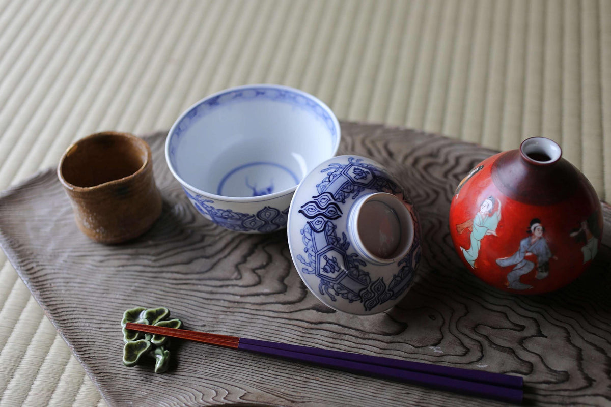 a variety of Japanese-style ceramic items, including a bowl, a vase, and a cup, arranged on a wooden surface.