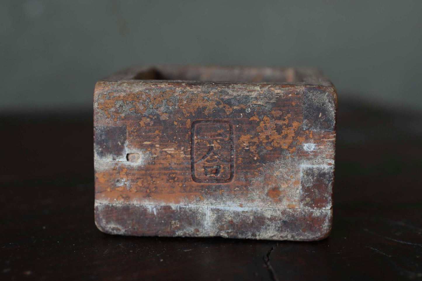 An old, weathered wooden box with a faded, rust-colored surface.
