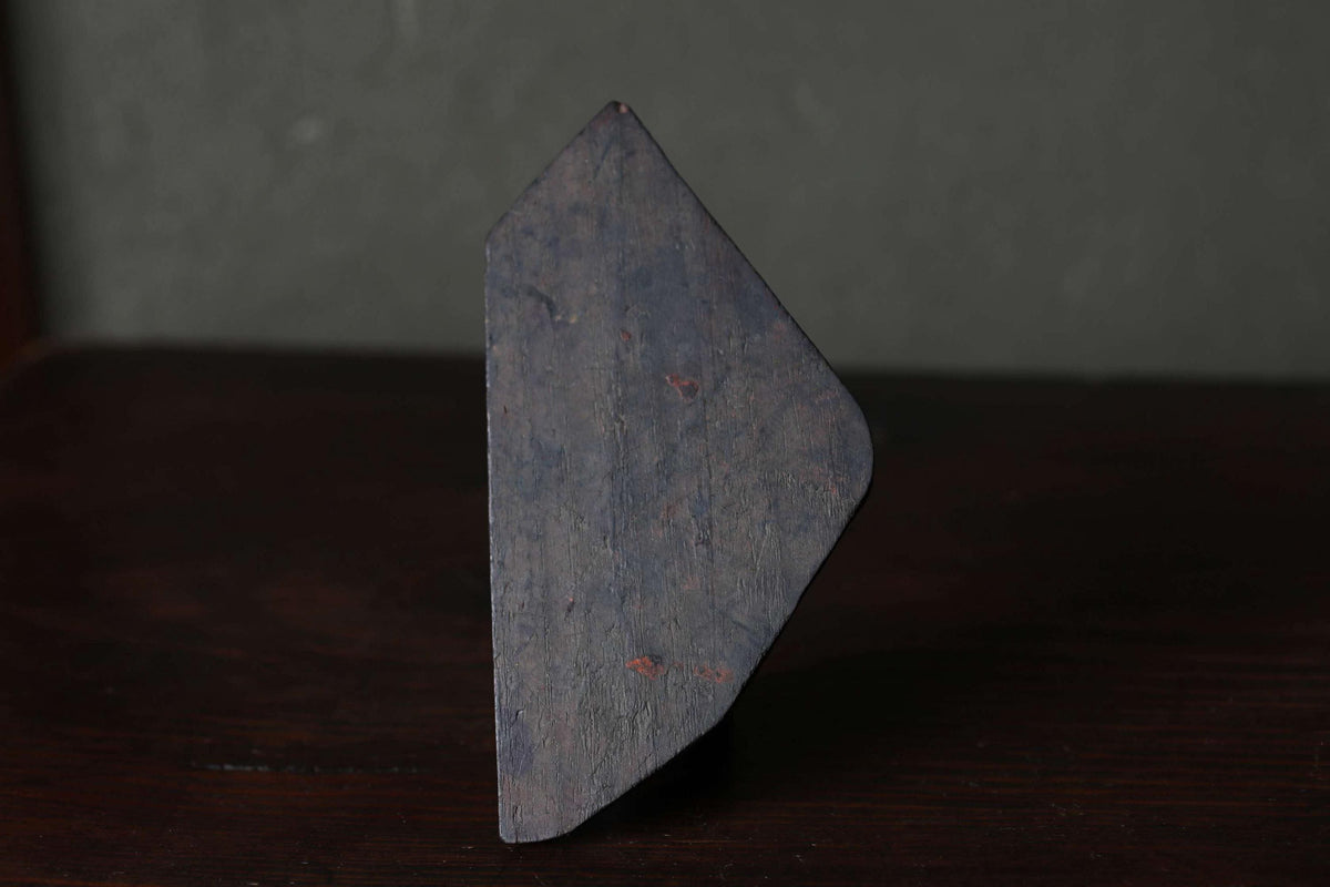 A dark, triangular-shaped object is sitting on a dark wooden surface.