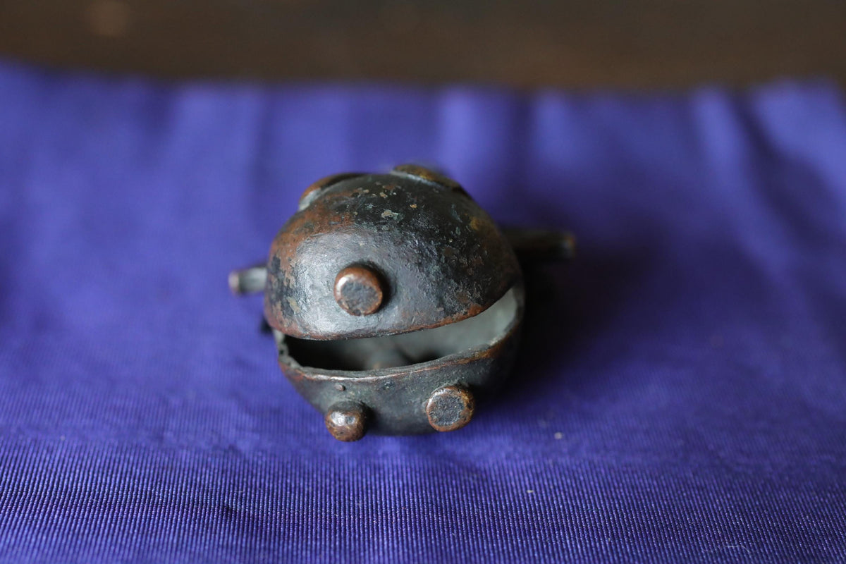 A small, round metal object with a hole in the center, sitting on a blue fabric surface.