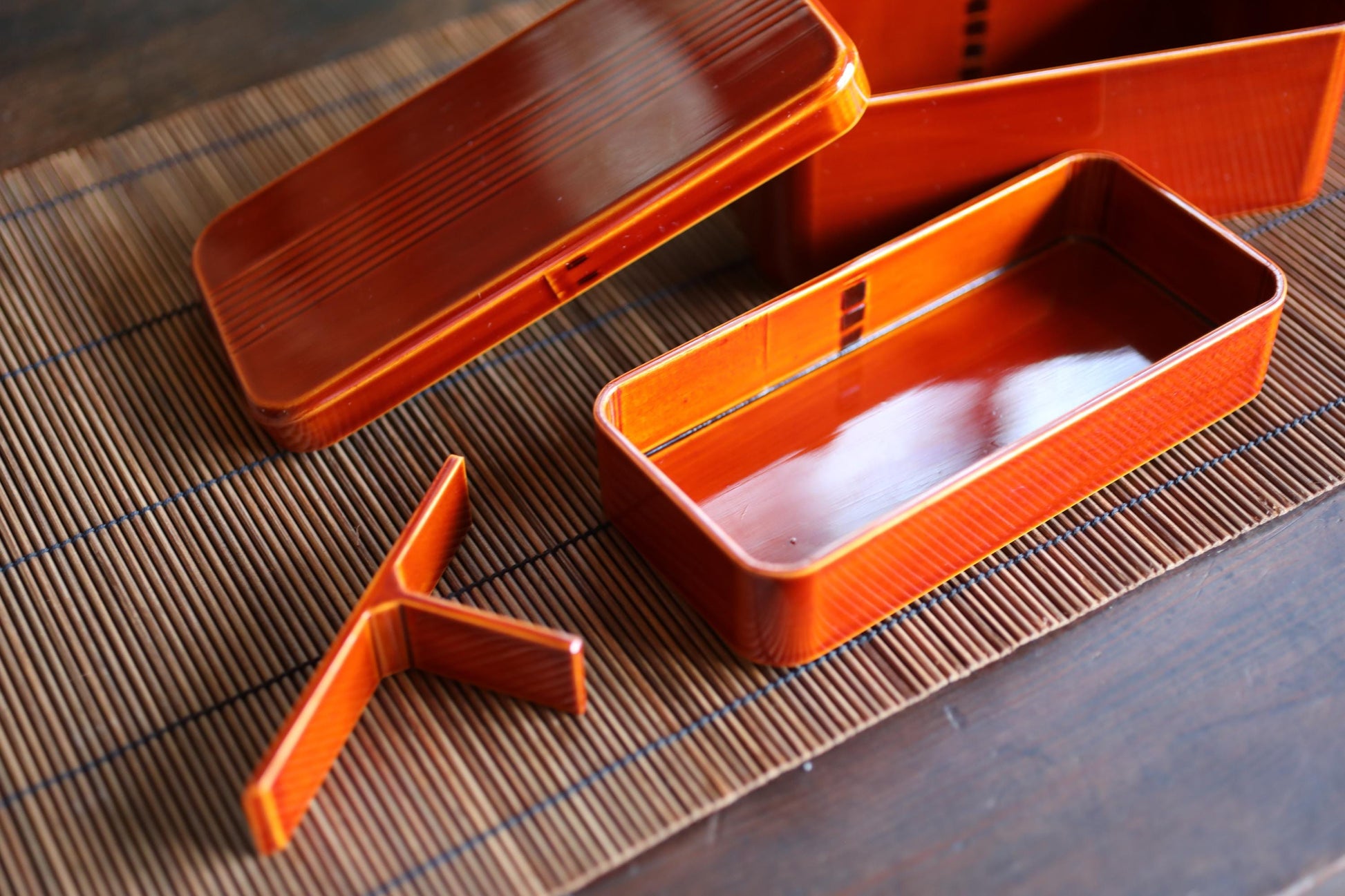 a close-up view of a wooden table with several orange bento box containers placed on it.