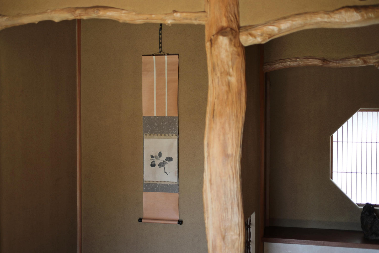 以下が含まれることがあります： 壁に掛けられたベージュと茶色の巻物。花柄のデザインと、その上に木製の梁がある。