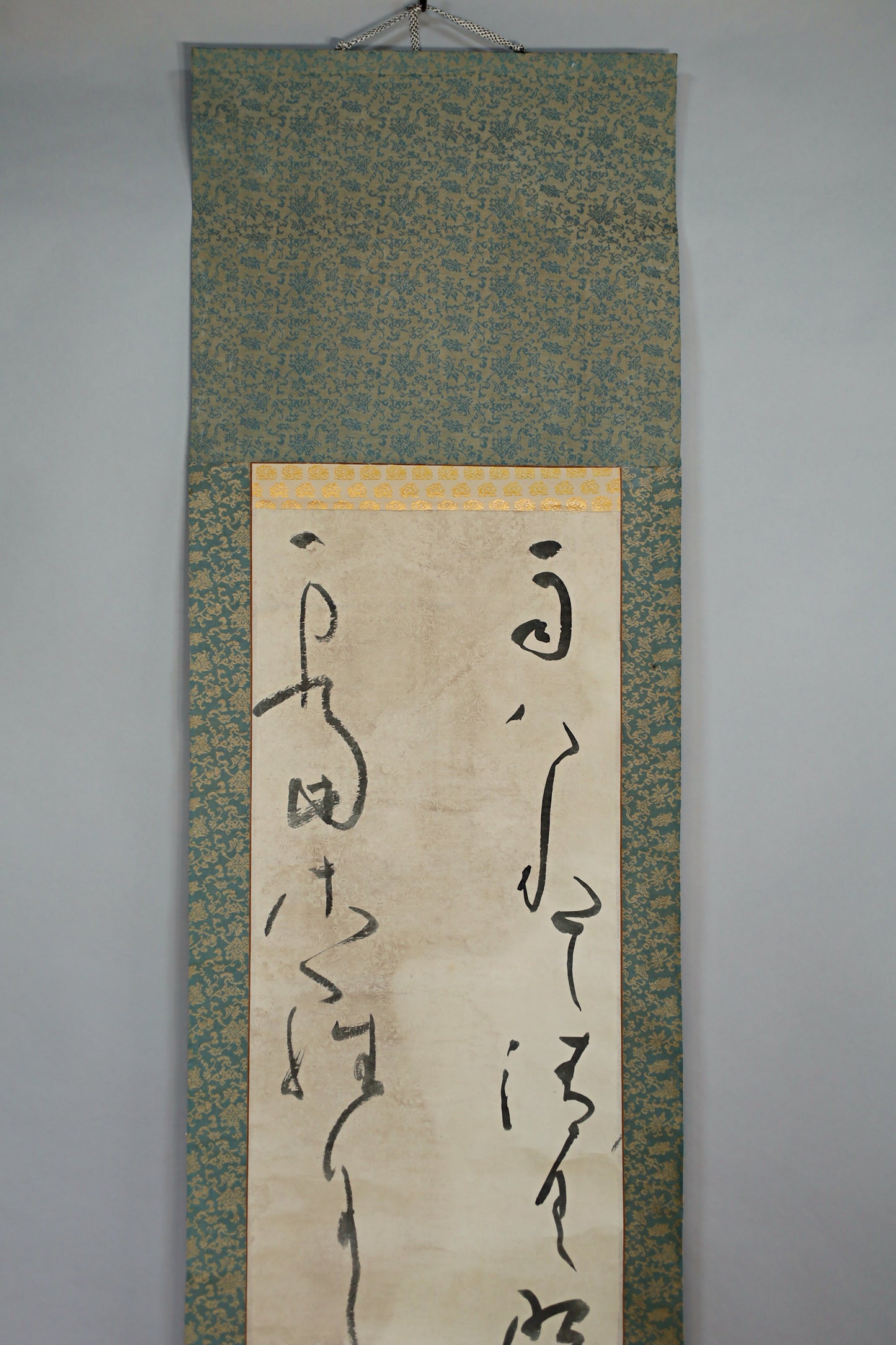 a scroll with Japanese characters on it, hanging on a wall.