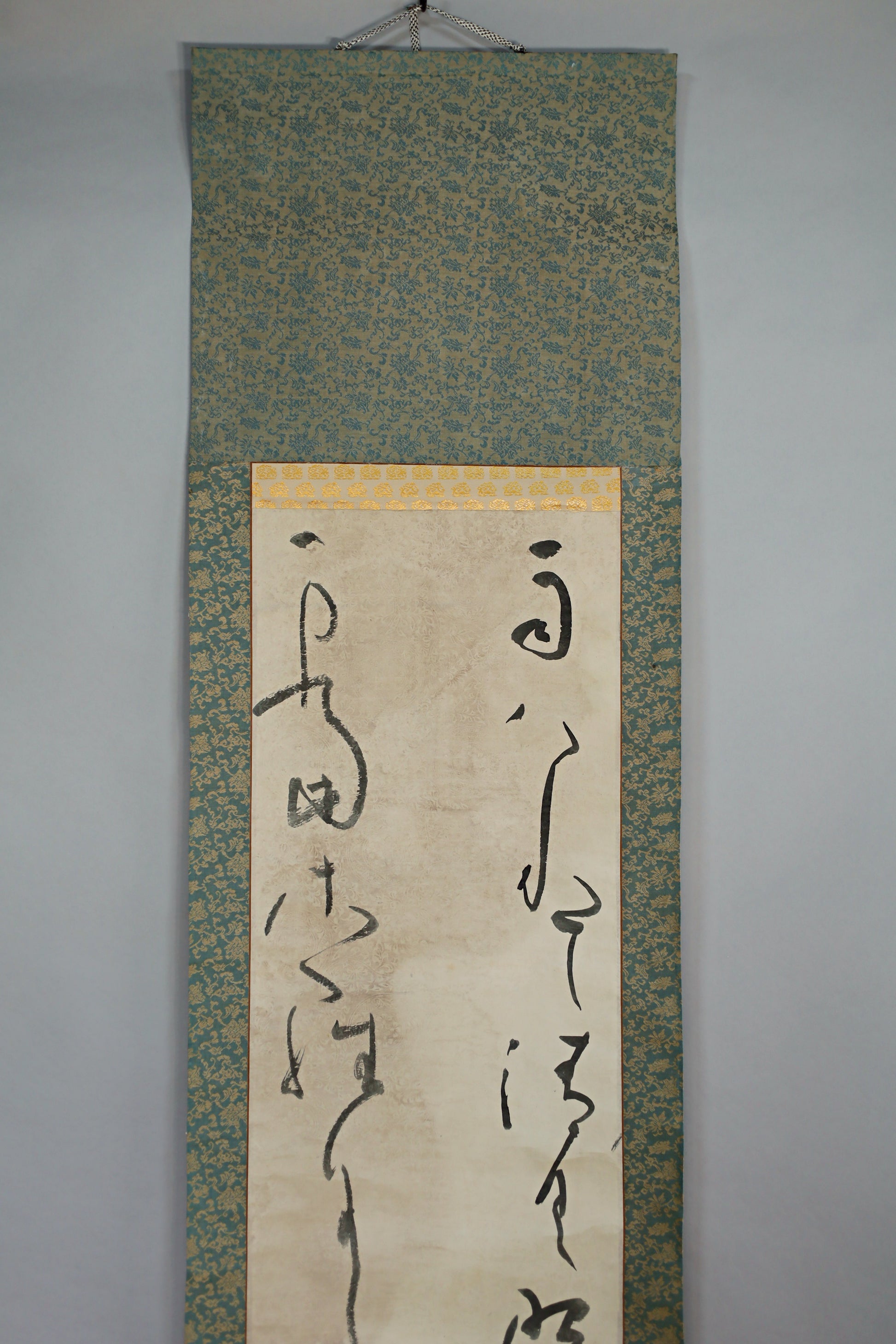 a scroll with Japanese characters on it, hanging on a wall.