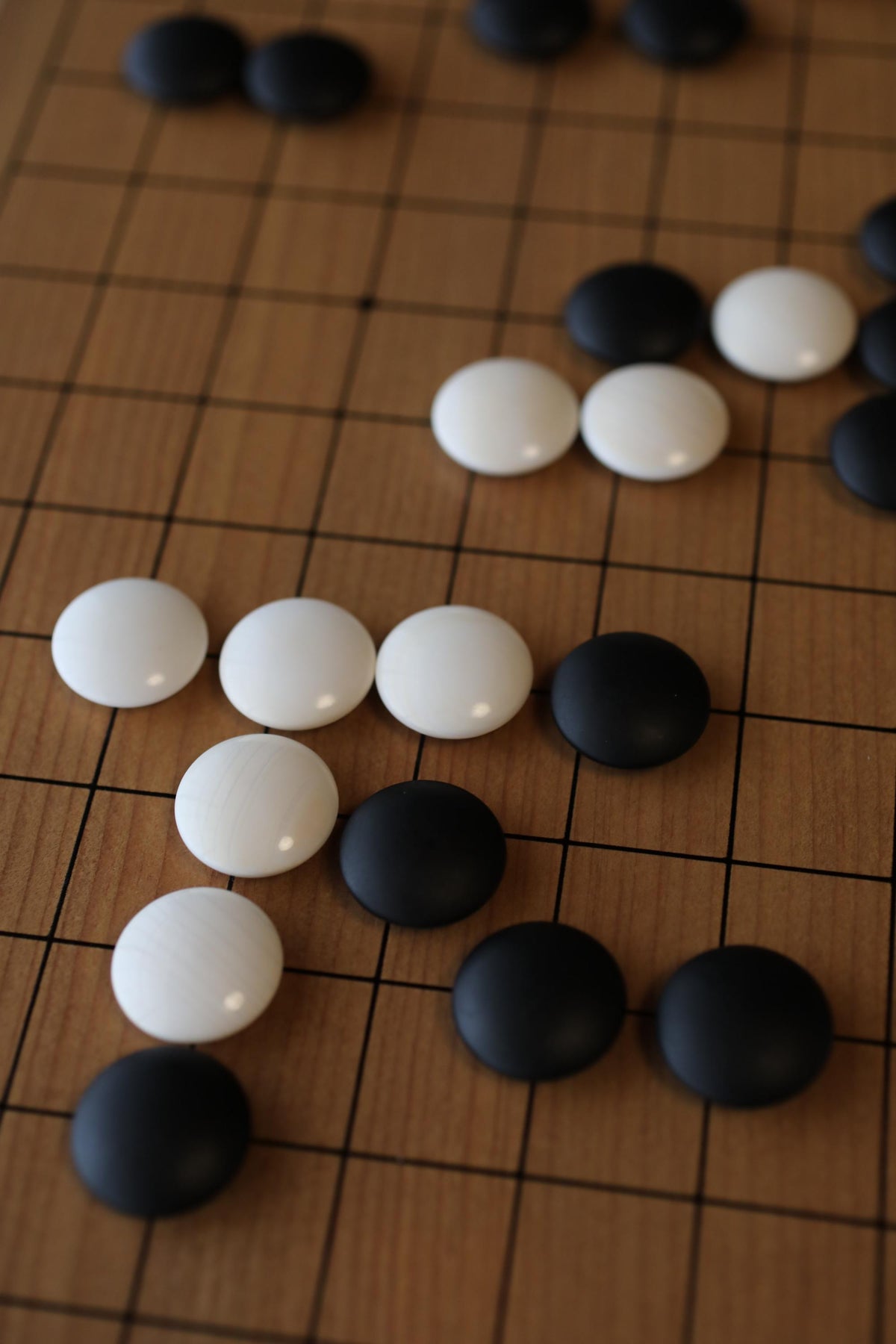 a close-up view of a wooden board with several black and white game pieces scattered across it.