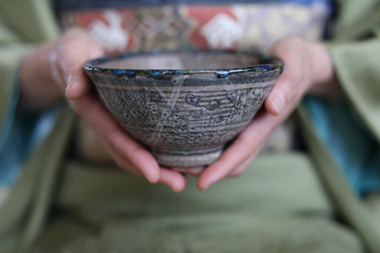 A person's hands holding a ceramic bowl with a patterned design.