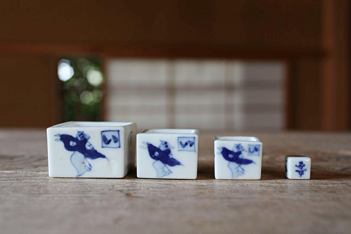 Three small ceramic containers with blue and white designs are arranged on a wooden surface.