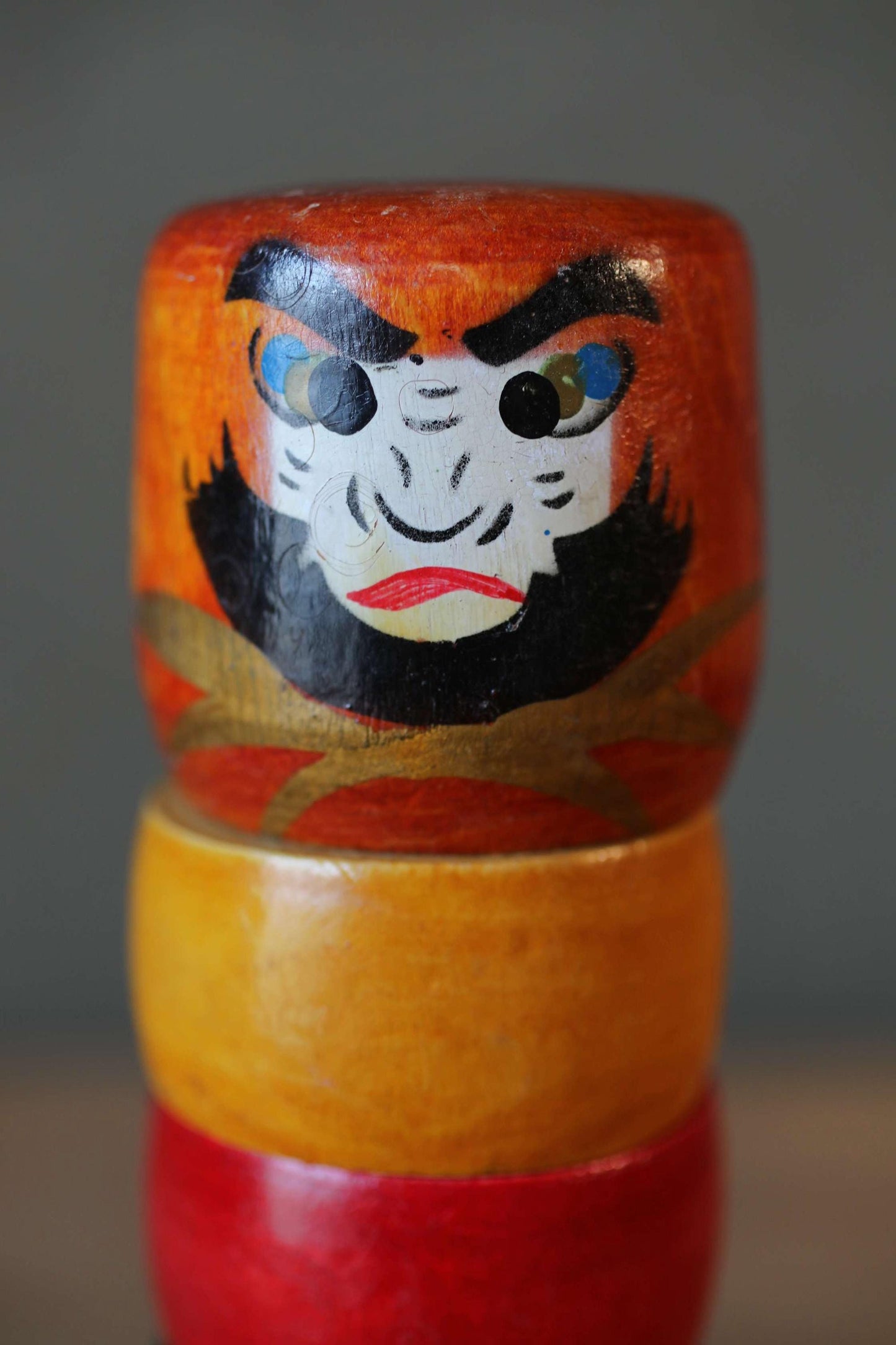 A colorful wooden doll with a face painted on it, sitting on top of two stacked wooden dolls.