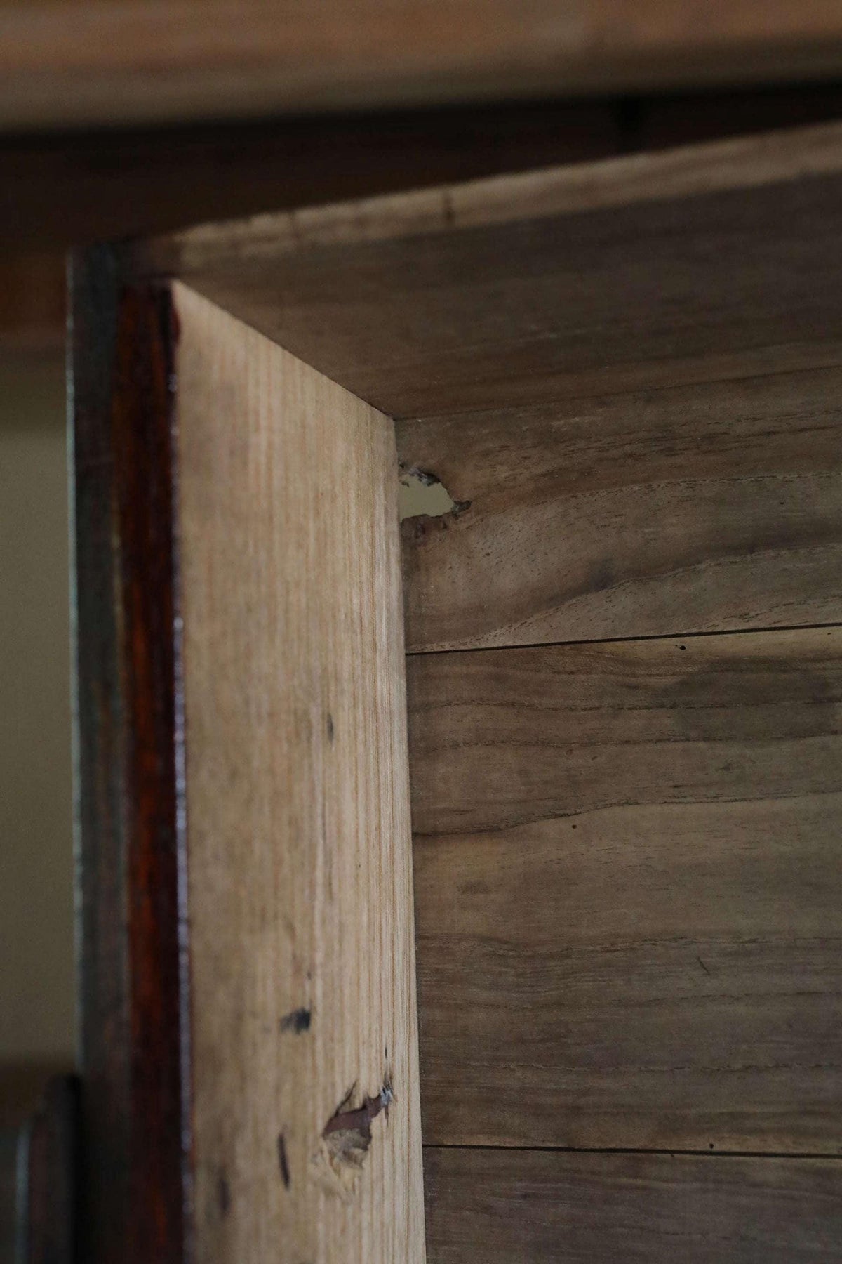 a close-up view of a wooden surface, possibly a piece of furniture or a wall, with visible grain and texture.