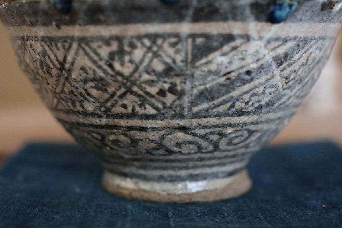 A close-up view of a decorative ceramic bowl with intricate patterns and designs, resting on a dark surface.