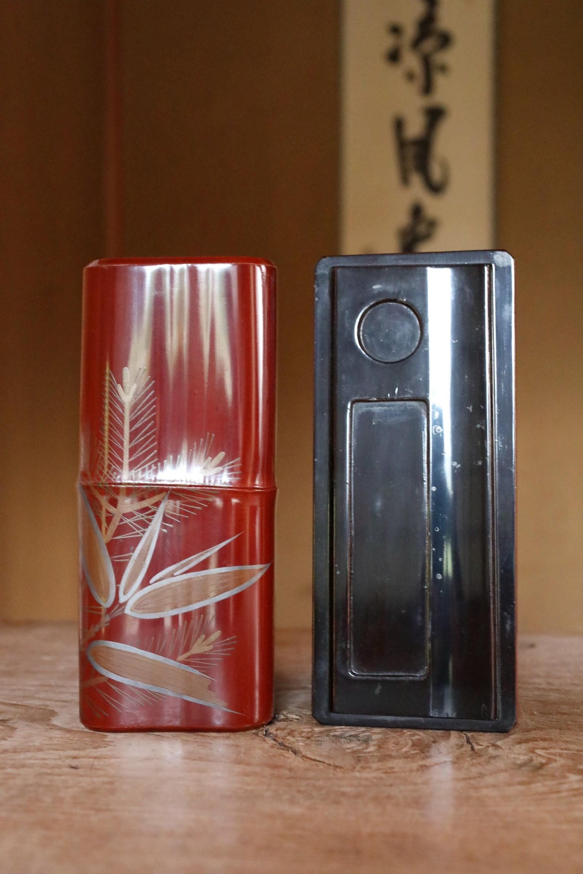 two objects placed on a wooden surface, one red and one black, with a background that includes some text.