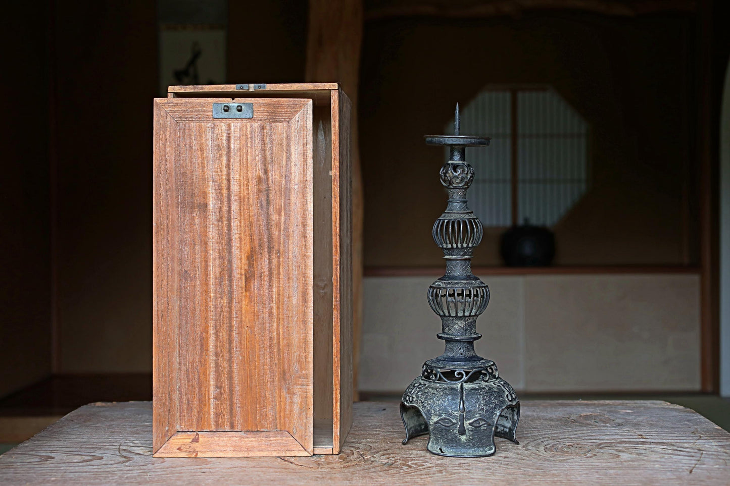a wooden box and a metal candlestick holder placed on a wooden surface.
