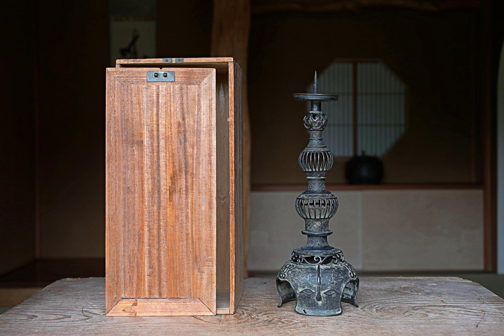 a wooden box and a metal candlestick holder placed on a wooden surface.