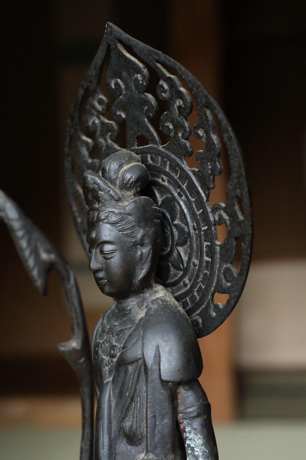 A close-up image of a black metal statue of a deity, with intricate designs and patterns on the headdress.