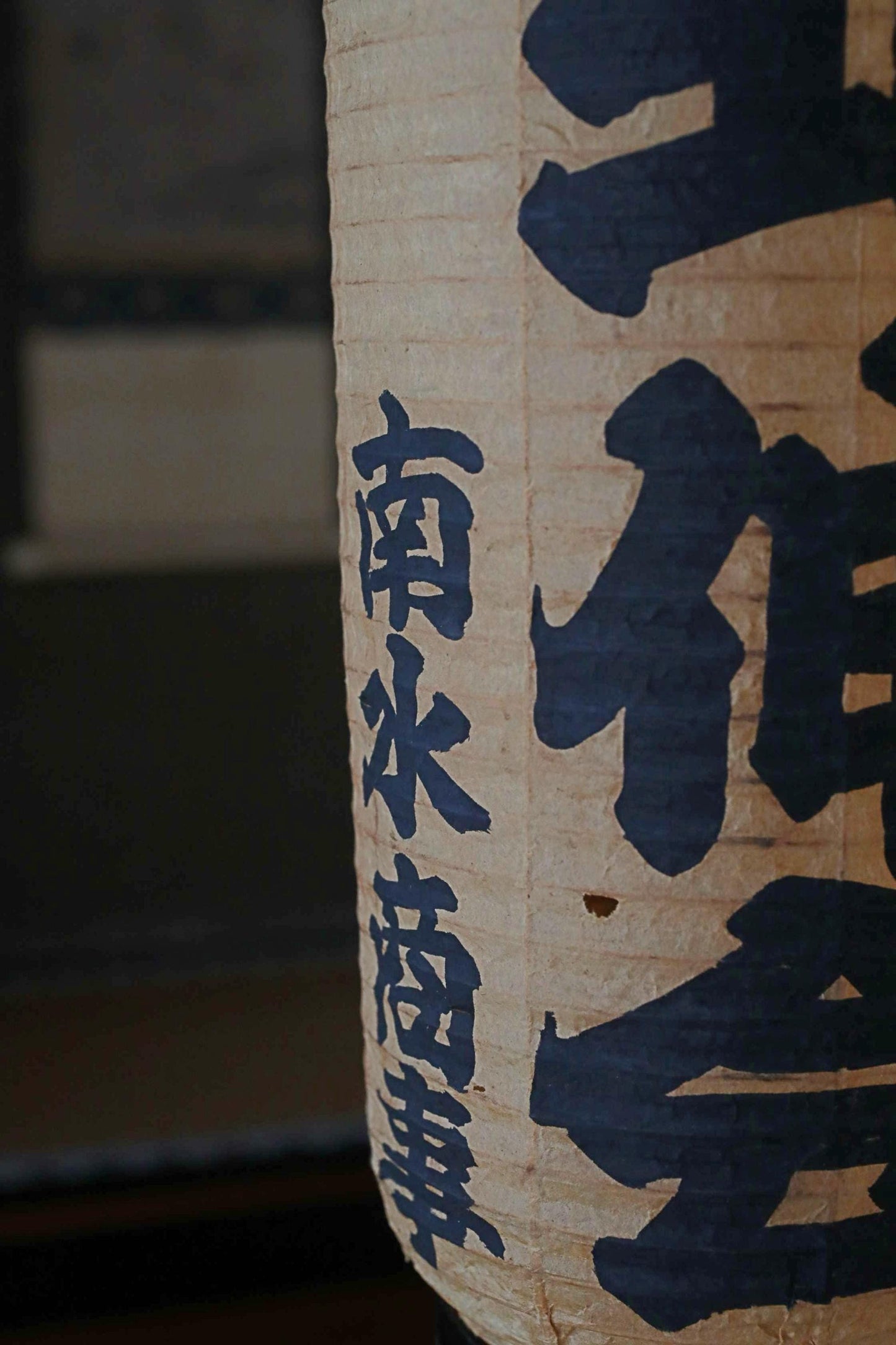 a close-up view of a paper lantern with Japanese characters painted on it.