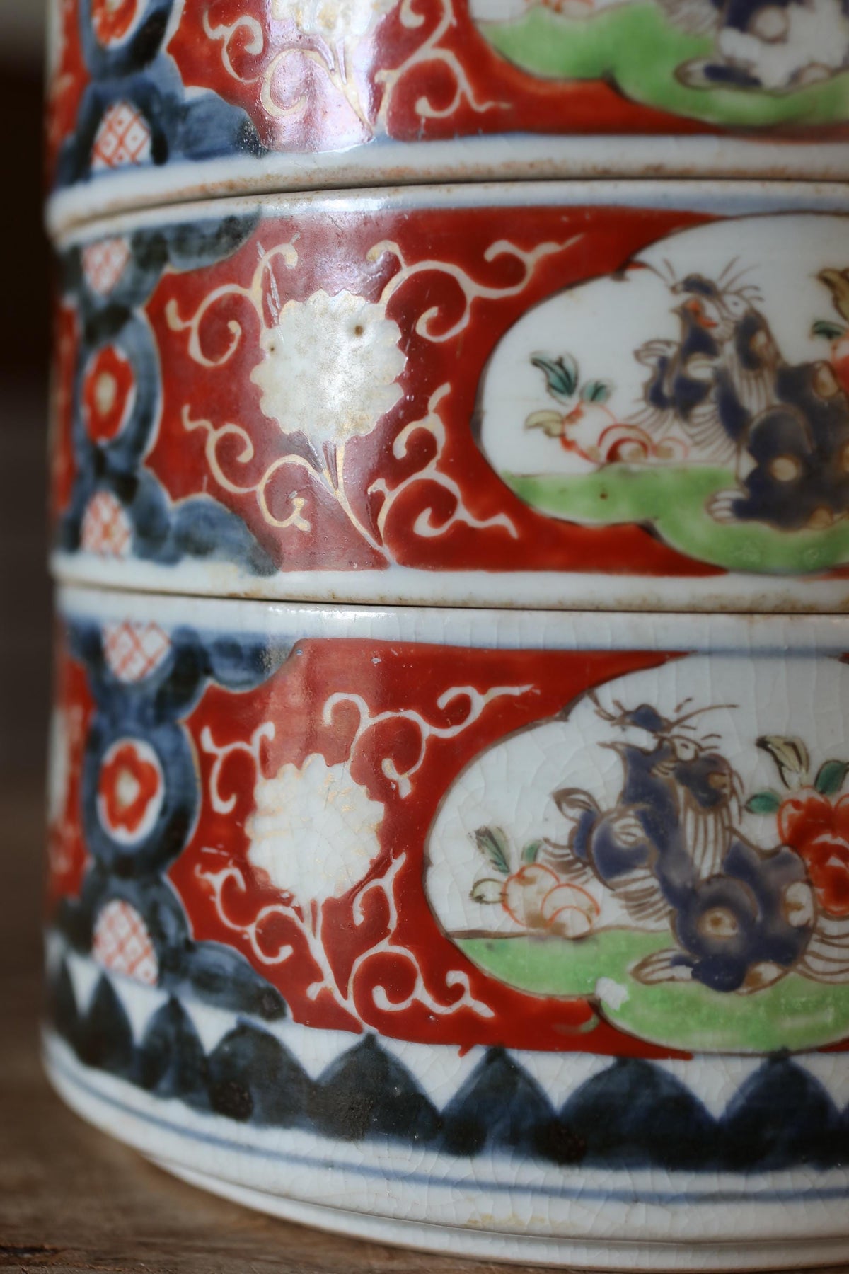 A close-up view of a decorative ceramic vase with intricate floral and animal designs in red, white, and blue colors.