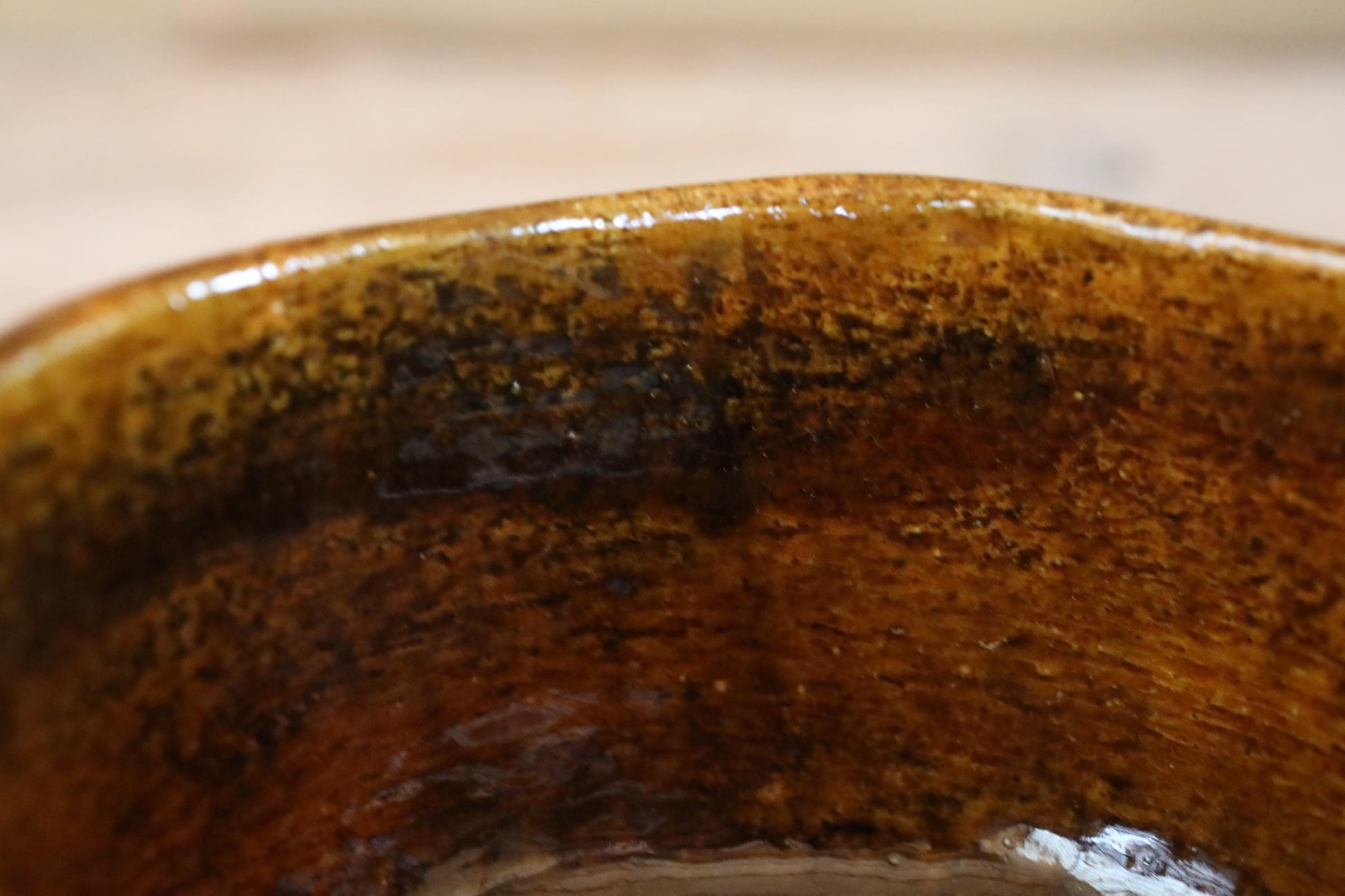 A close-up view of a brown, textured ceramic bowl or dish with a slightly worn appearance.