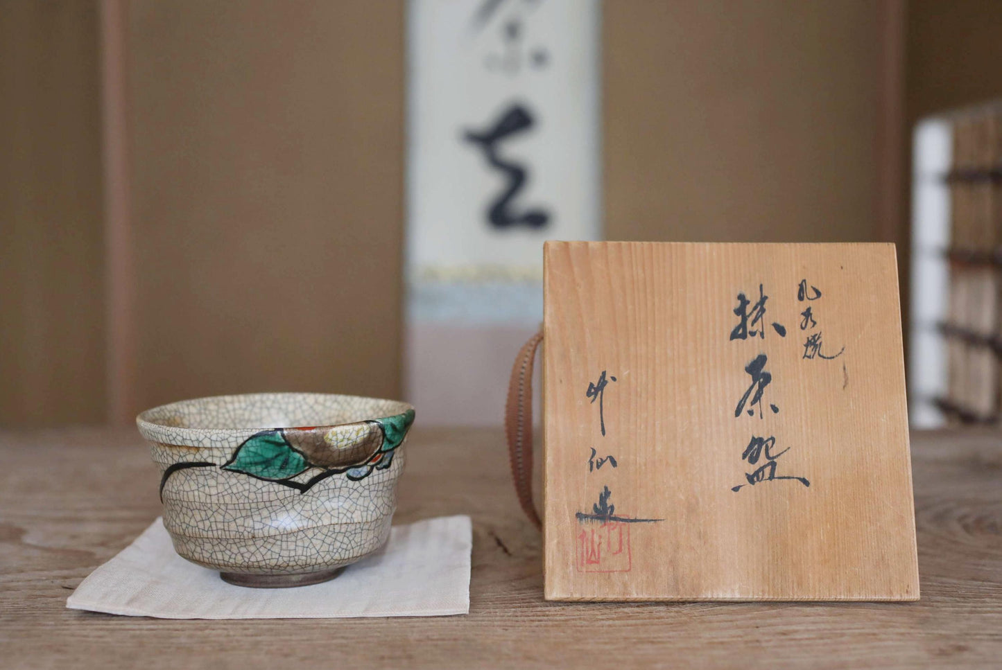 a ceramic bowl with a leaf design and a wooden sign with Japanese characters on a wooden surface.