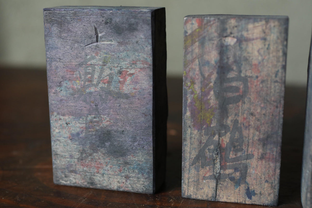 Two weathered wooden blocks with graffiti on them, sitting on a wooden surface.