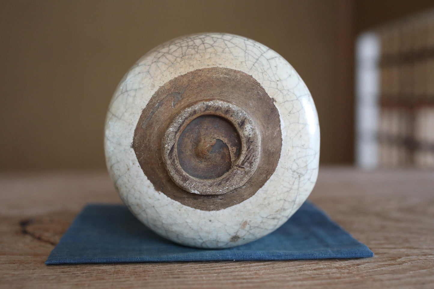 A white ceramic bowl with a brown rim sits on a blue cloth on a wooden surface.