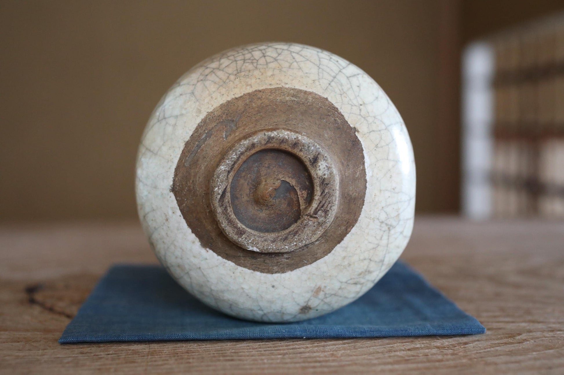 A white ceramic bowl with a brown rim sits on a blue cloth on a wooden surface.