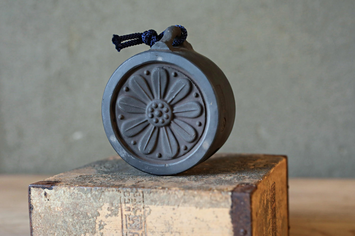 A black, circular object with a flower-like design on it, sitting on a wooden surface.