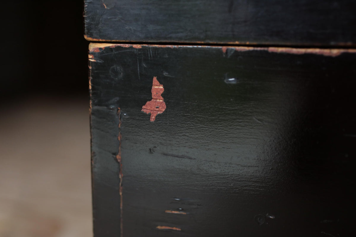 a close-up view of a black wooden surface with a small red mark or stain on it.
